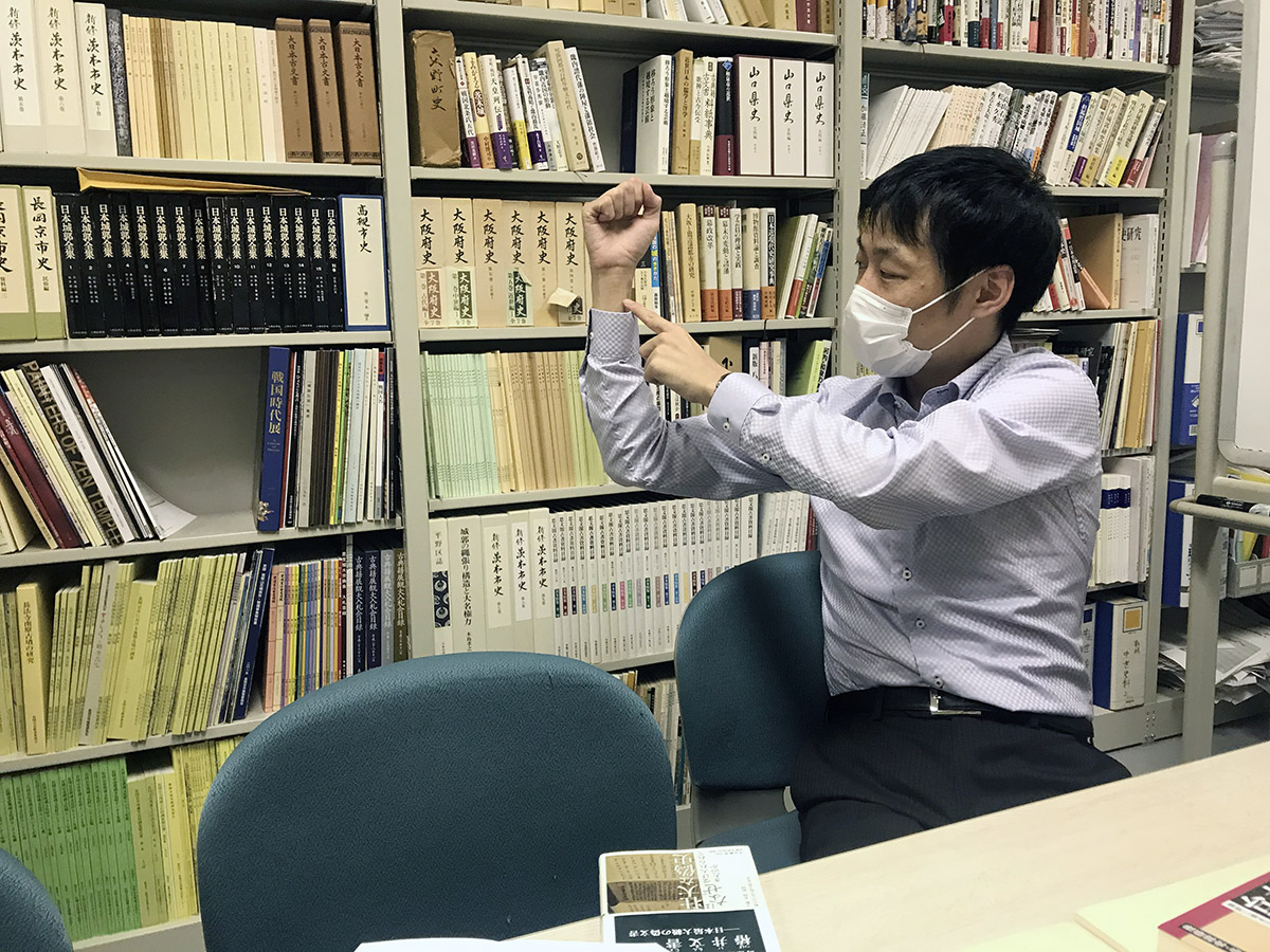 ▲腕を使って歴史の積み重ねを説明する馬部さん
