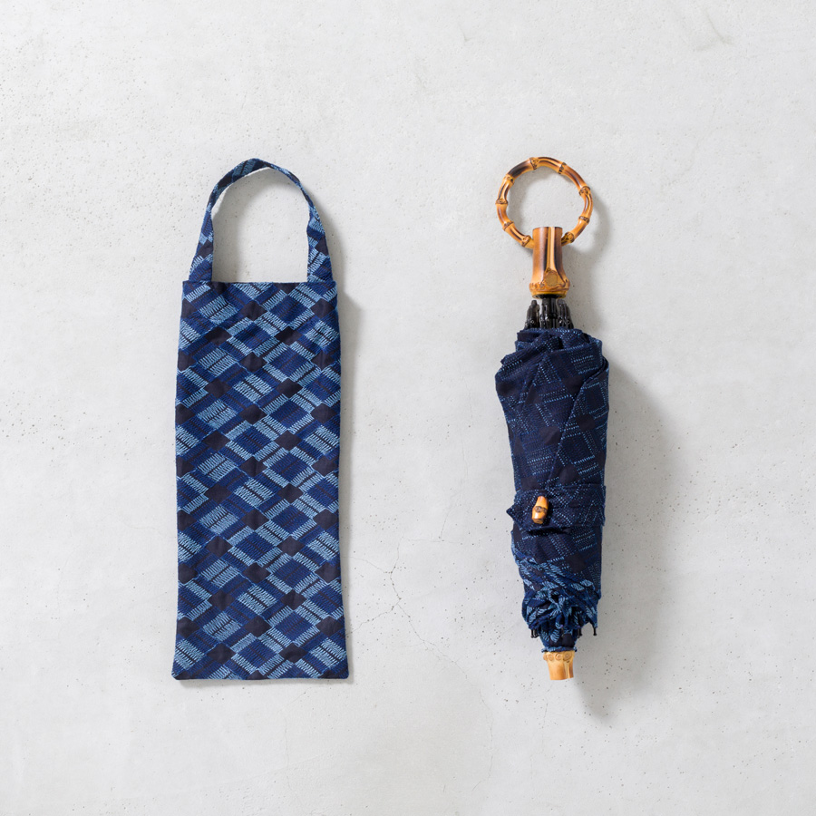 ▲「BLUE/NAVY」の傘には、
持ち手やボタン、先端の部分も
全て竹のパーツを使用しました。
長いままの状態でも畳んで持ち歩けるよう、
ネームバンドを取り付けています。