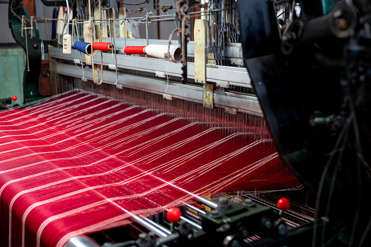 ▲綜絖（細い金属の棒）の穴に、経糸を１本ずつ通しています。