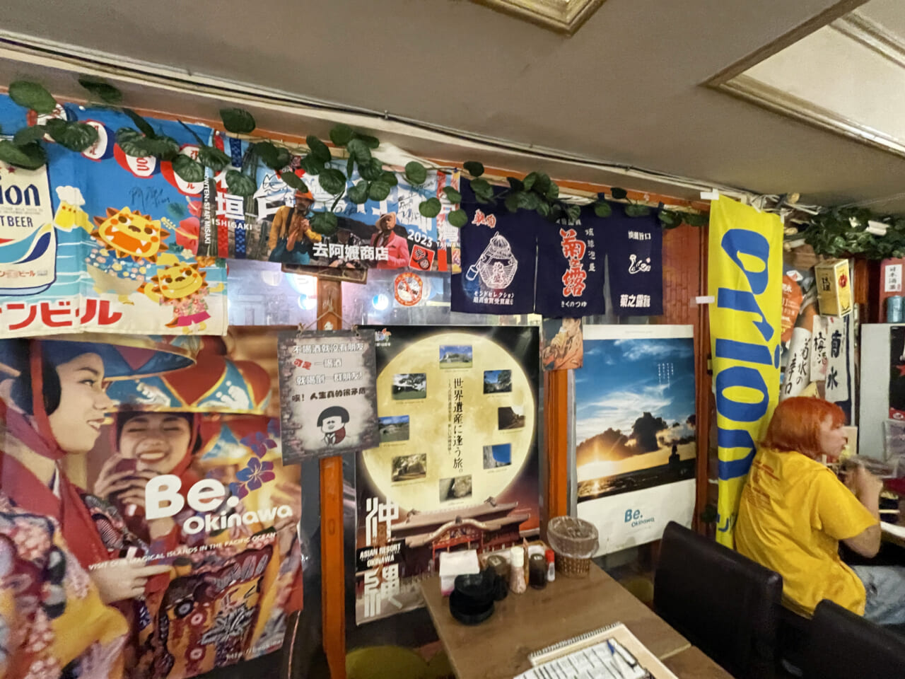 「圓酒（まるさけ）」は店中に沖縄のポスターや写真が張り詰められ、思いっきり沖縄の大衆酒場の雰囲気。