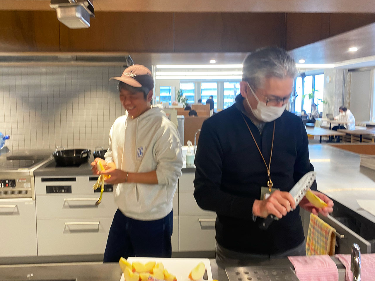 ▲かわかみさん（右）。これは社内イベントでりんごをむいているところ。