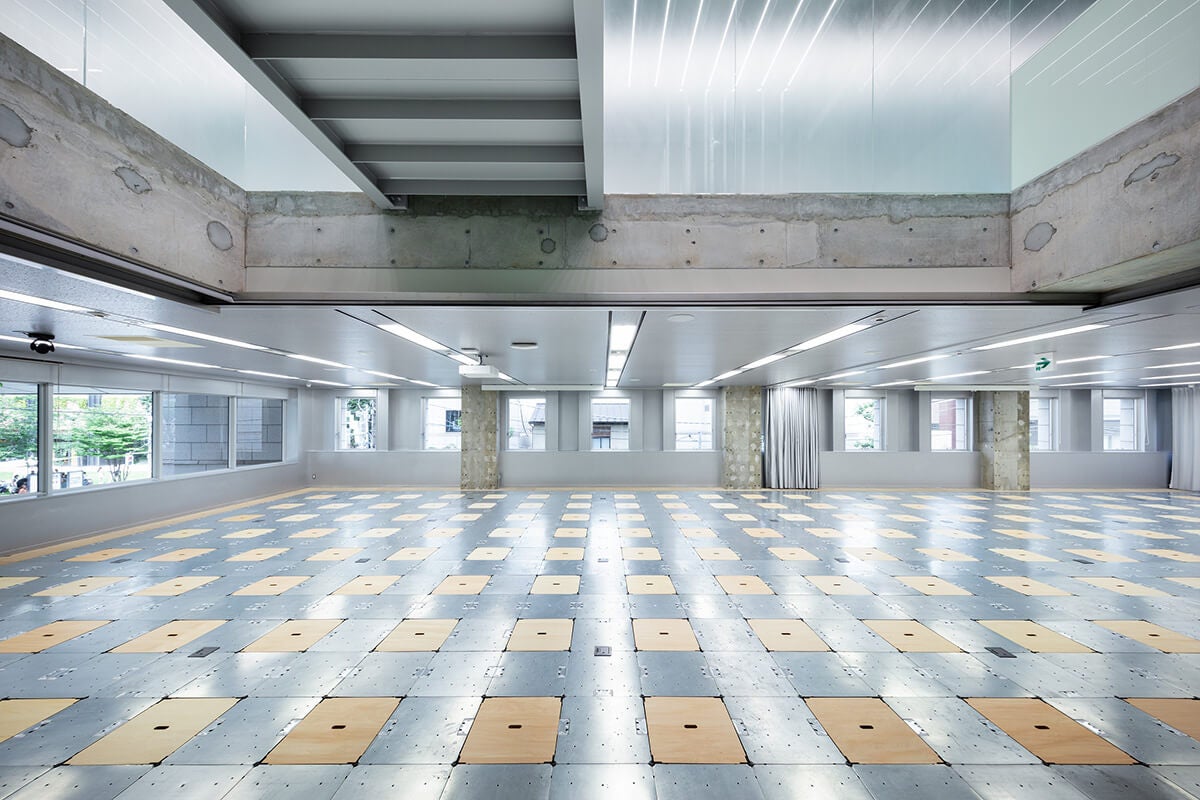 JINSさんのオフィスにある、広々したスペース。床はつるつるした銀と木目が交互に並んでいます。白っぽい照明で明るい雰囲気です。