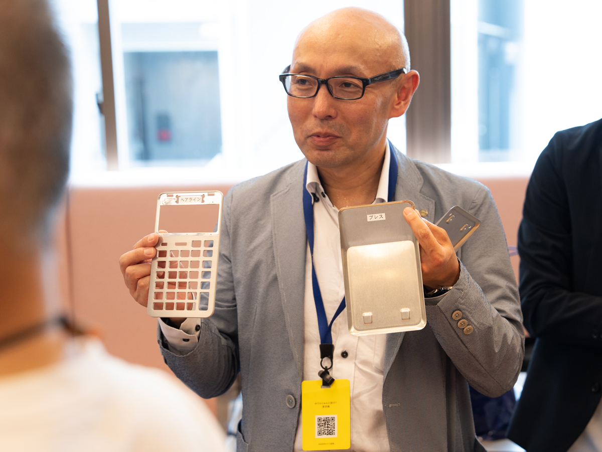 ▲左側が、S100に使われている、アルミを切削したボディ。右は金属板に圧力をかけて作ったS100の背面のパーツです。