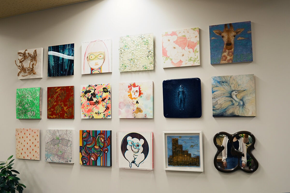 JINSさんのオフィスの壁。小さな絵や鏡が18枚飾られていておしゃれな雰囲気です。