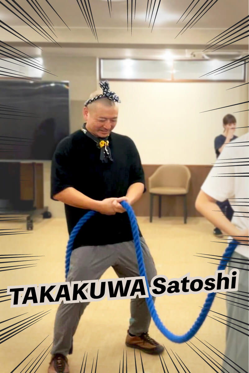 新メンバーの高桑さんがつなをひいています。スキンヘッドの頭にはリボンのようにバンダナを巻いています。