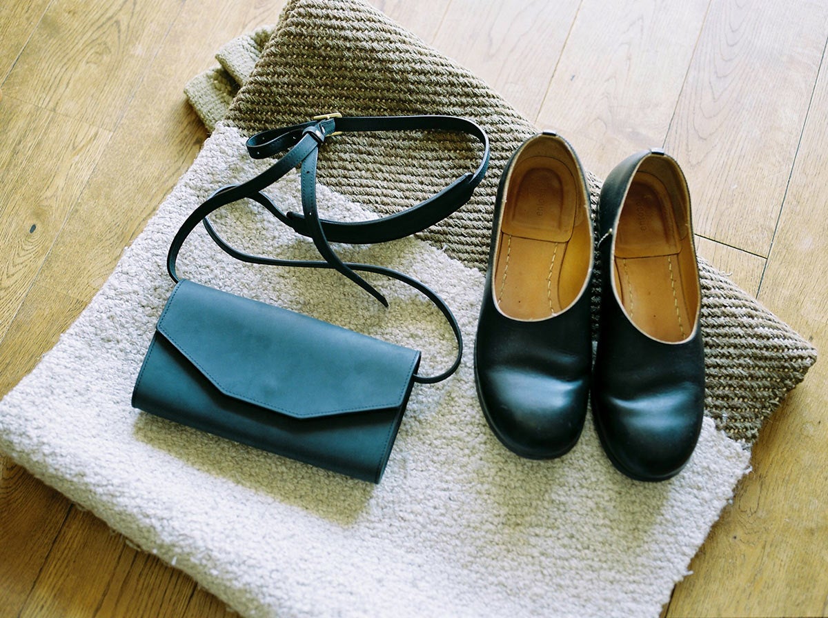 おさいふショルダーとentoanの黒い靴が柔らかい光に照らされて置かれている