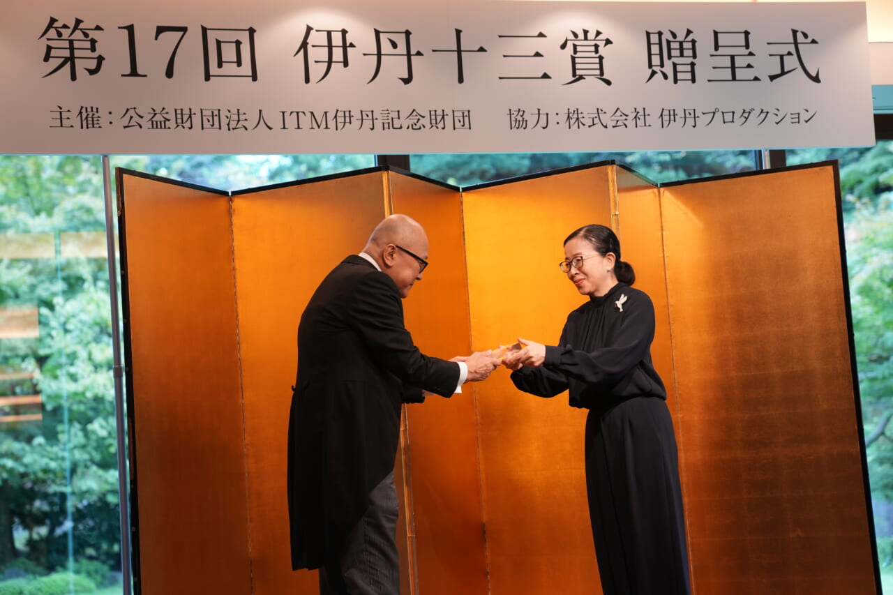 酒井順子さんが、壇上で山田五郎さんに賞状を手渡しています。