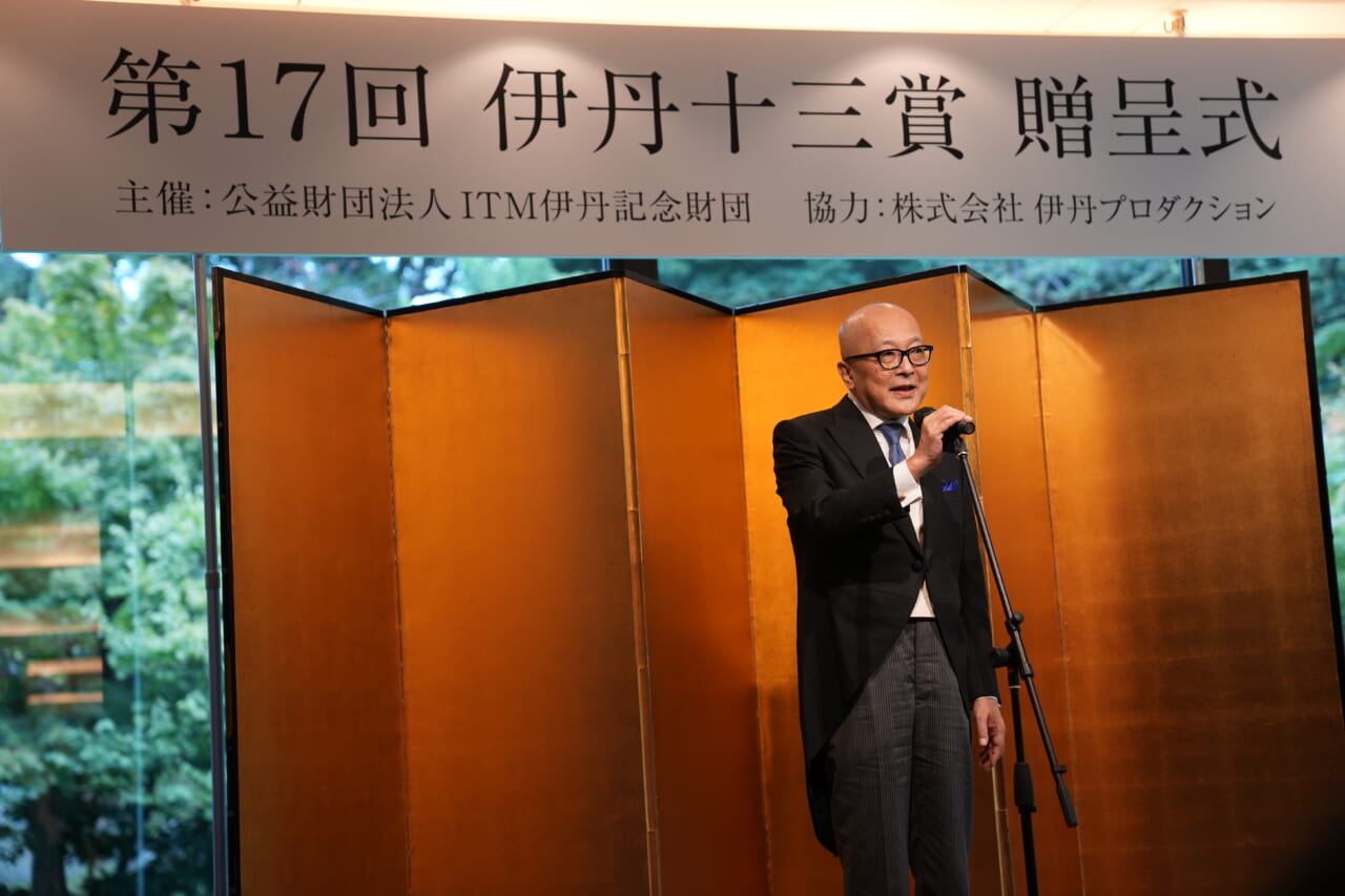 山田五郎さんが壇上でマイクに向かって話しています。