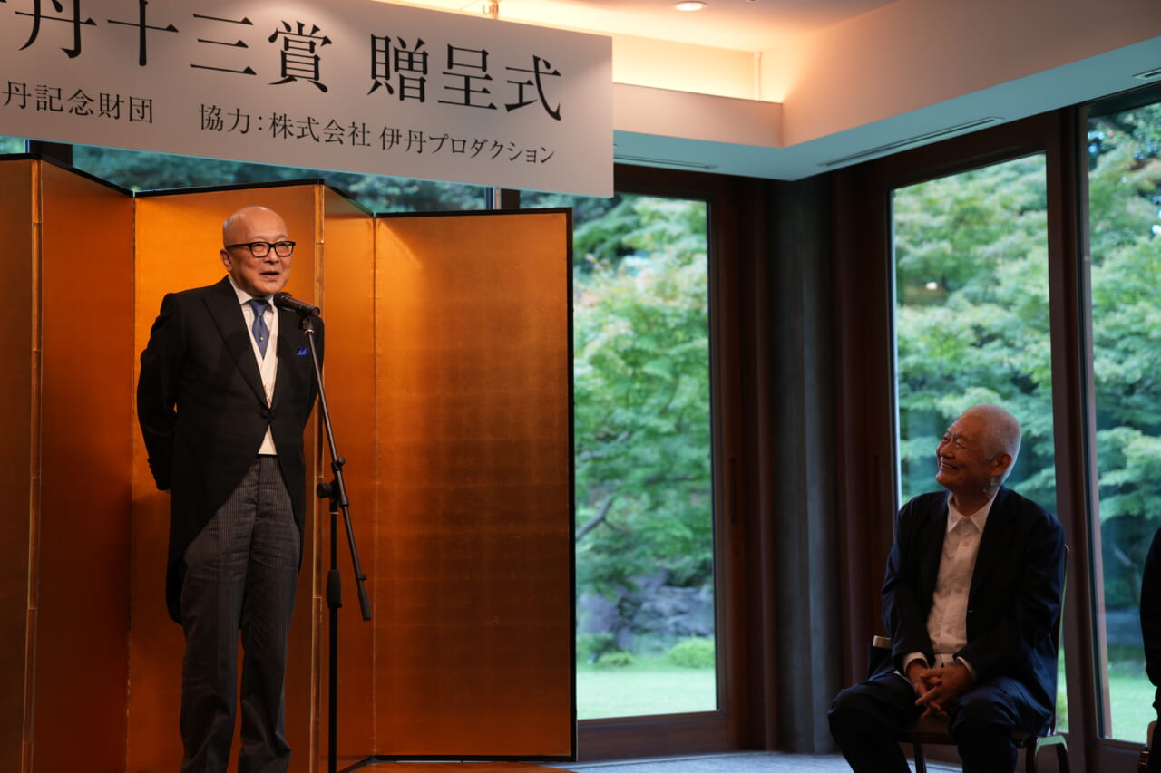 山田五郎さんが壇上で話し続けています。ステージの右側で、南伸坊さんが嬉しそうに山田さんを見上げてほほえんでいます。