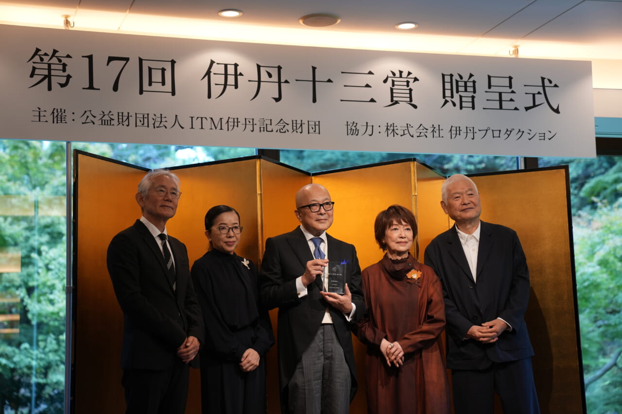 「第17回　伊丹十三賞　贈呈式　主催：公益財団法人ITM伊丹記念財団　協力：株式会社　伊丹プロダクション」という文字の書かれたパネルの下で、金の屏風の前に、左から周防正行さん、酒井順子さん、山田五郎さん、宮本信子さん、南伸坊さんが並んでいます。