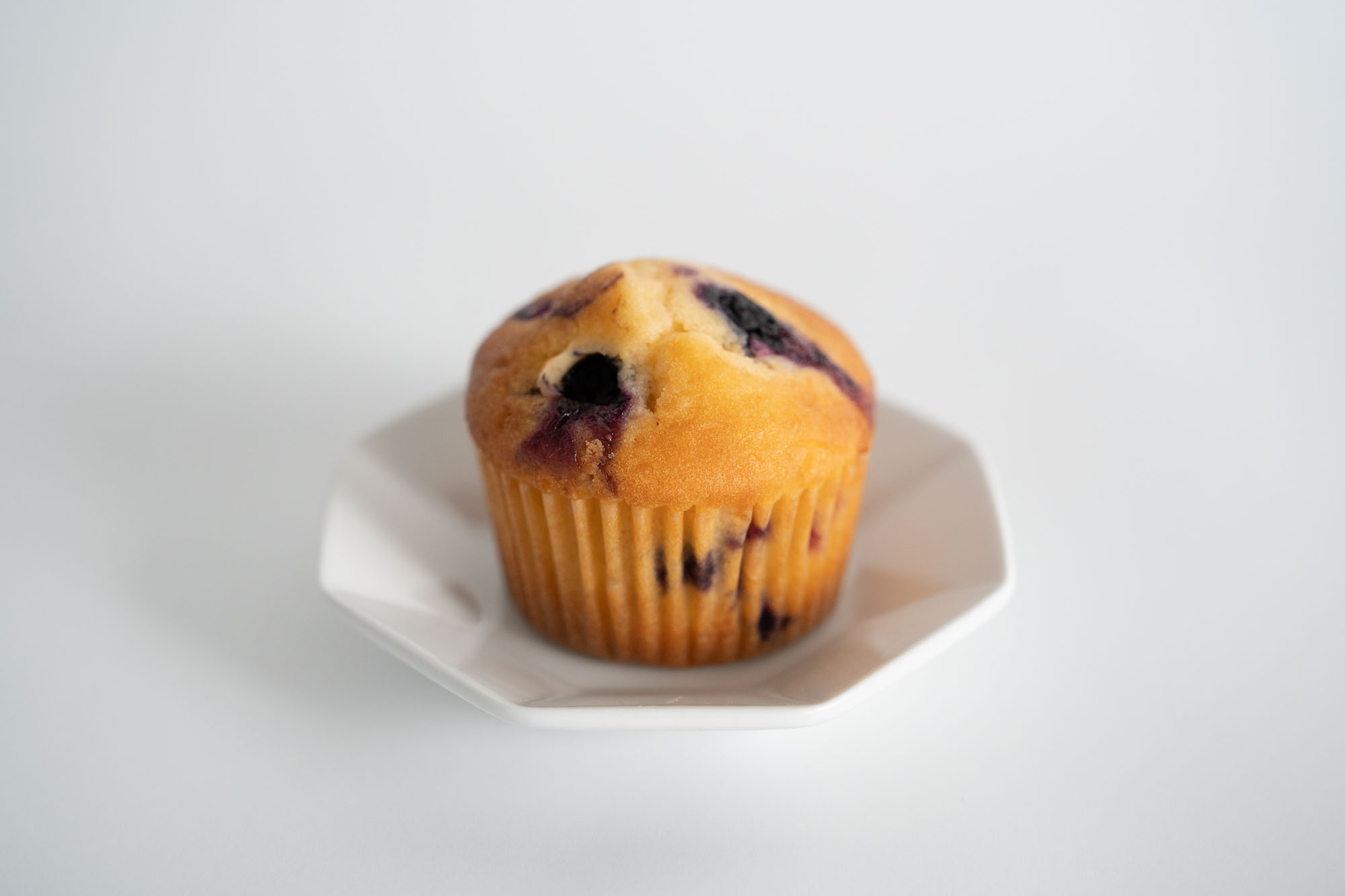 ブルーベリーがごろごろ入った食べ応えのあるマフィン。白いお皿に盛り付けられている。