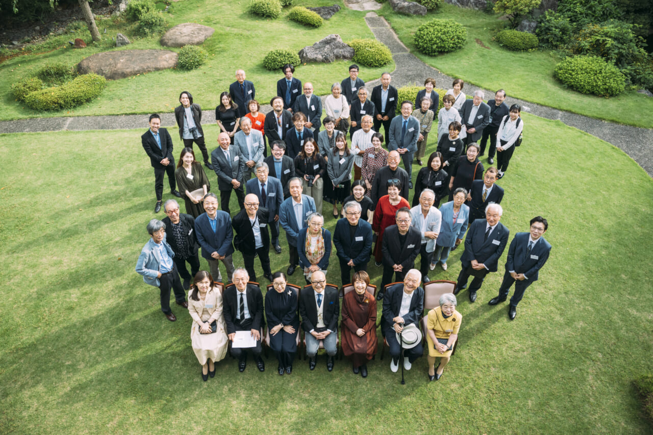 50名ほどの出席者全員が庭に並び、笑顔を浮かべています。
