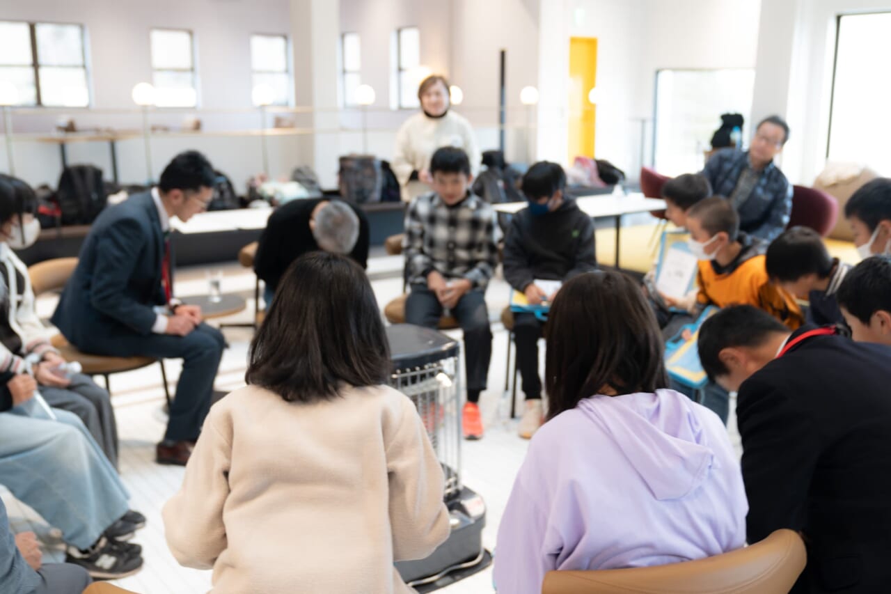 ストーブを囲んだ、約10名の白川小学校６年生のみなさんと糸井重里が、頭を下げている。