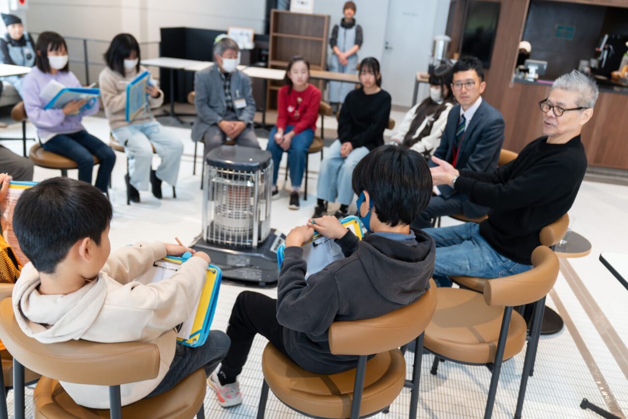 白川小学校のみなさんと糸井重里が輪になって話している。質問したHさんと糸井は互いに顔を見合っている。