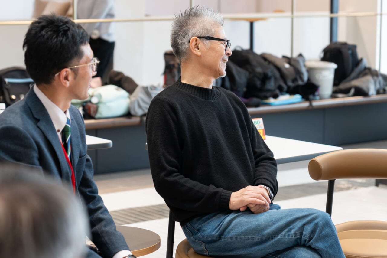 糸井が椅子にゆったりと座って笑っている。