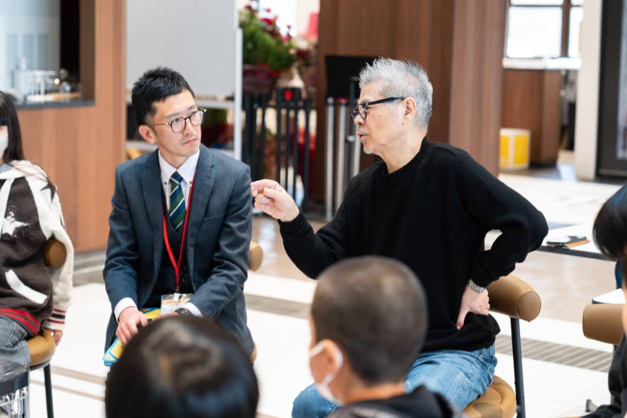 糸井が話している。先生は糸井のほうを向いて聞いている。