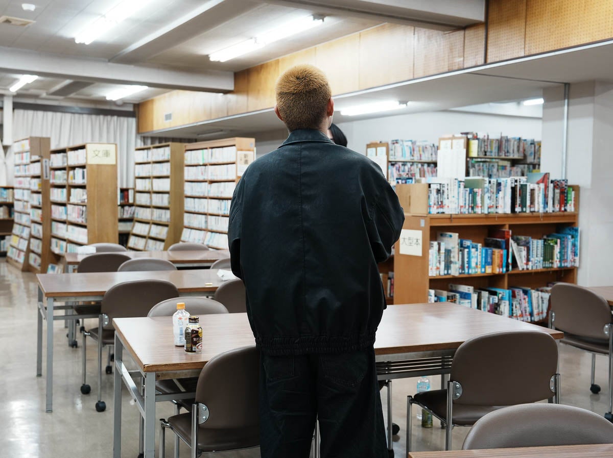 短い金髪に黒いだぼっとした服装の男の子の後ろ姿