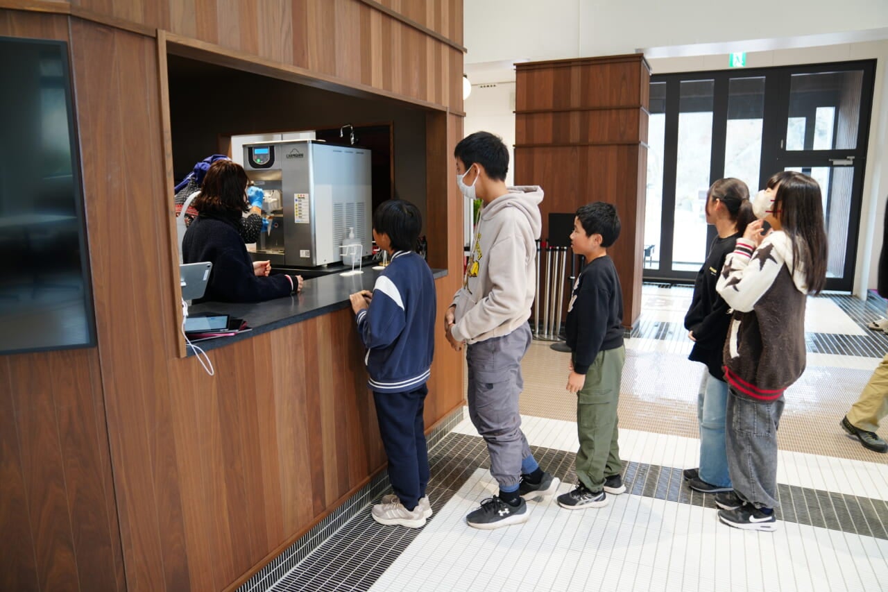 生徒さんたちが「ほぼの駅AKAGI」の売店のカウンターでソフトクリームを待って列をつくっている。