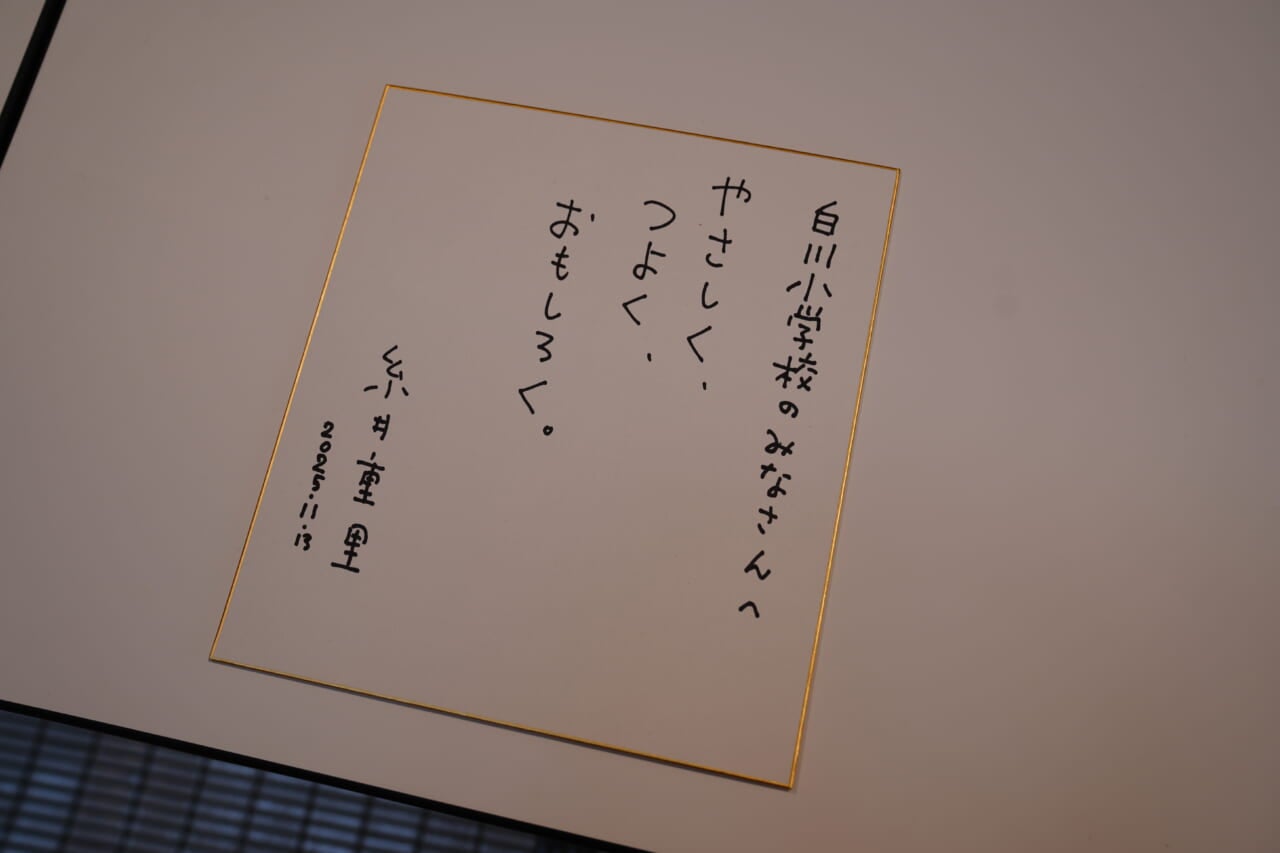 糸井が白川小学校のみなさんに贈った色紙。「白川小学校のみなさんへ　やさしく、つよく、おもしろく。糸井重里　2025・11・13」と書いてある。