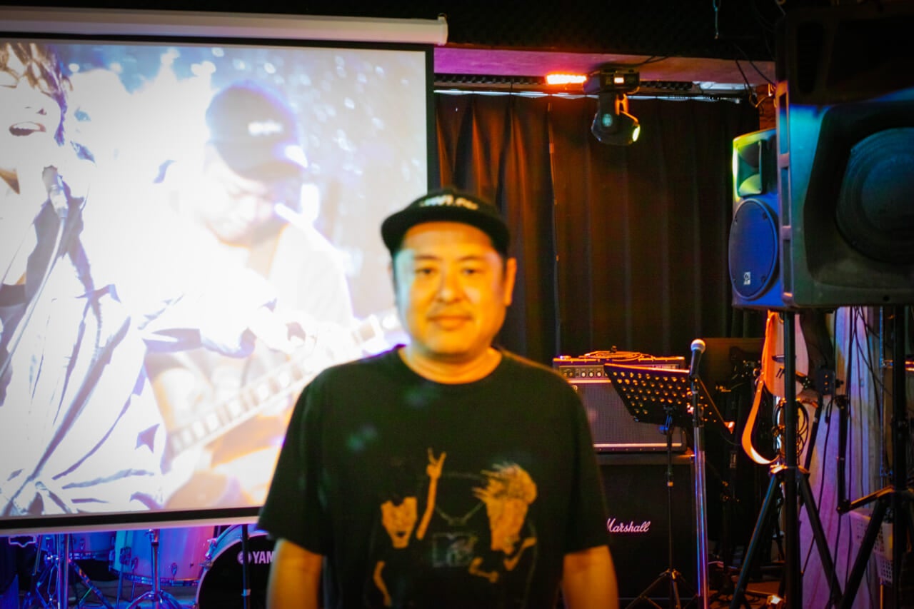 上映会場のひとつ、ライブハウス「CITY JACK」の根間タダシさん。通称たーしーさん。バンドのギタリストとしてメジャーデビューしていた過去を持つ。お店が素敵すぎて、お店の方にピントが合ってしまいました！　もちろん、たーしーさんもとっても素敵だったのですが。（撮影：奥野）