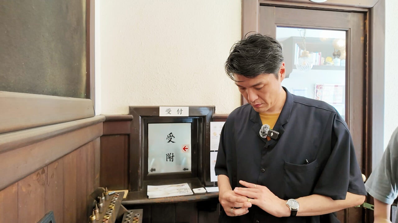 ▲壁際に置かれていたアクセサリーを試着してみる直太朗さん。
「お客さんが作ってくれて、置いてあるんです」と北浦さん。